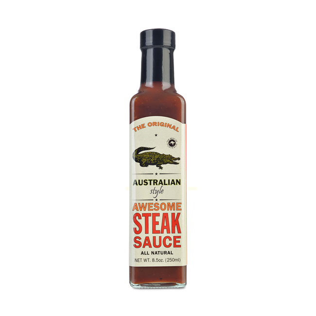 Auf dem Bild ist eine Flasche "Australian Awesome Steak Sauce" mit einem Fassungsvermögen von 250 ml zu sehen. Das Etikett zeigt einen Krokodil und hebt den australischen Stil sowie die natürliche Zutaten hervor.