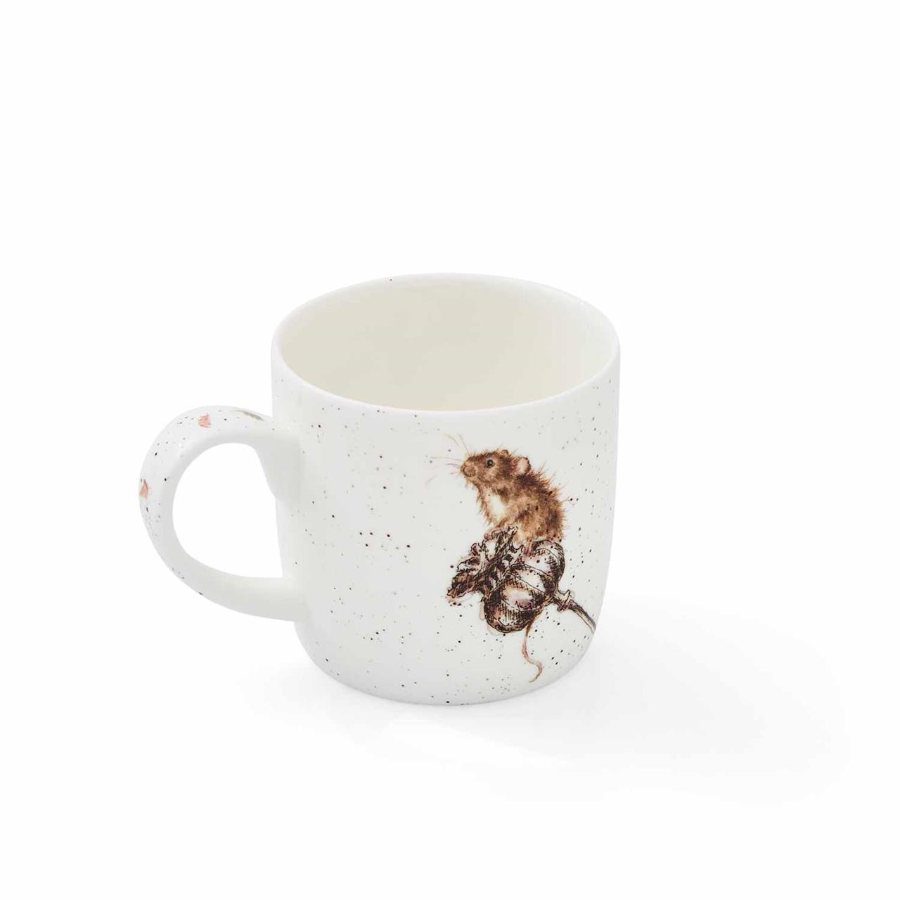 Auf der abgebildeten Tasse ist eine Maus zu sehen, die auf einer Eichel sitzt. Die Tasse ist weiß mit kleinen, dezenten Sprenkeln und hat ein Fassungsvermögen von 0,31 Litern.
