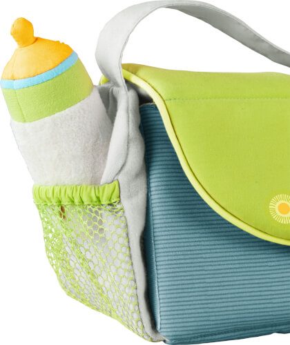 Auf dem Bild ist eine grüne und blaue Wickeltasche zu sehen. In der Seitentasche steckt eine Babyflasche mit einem gelben Deckel.