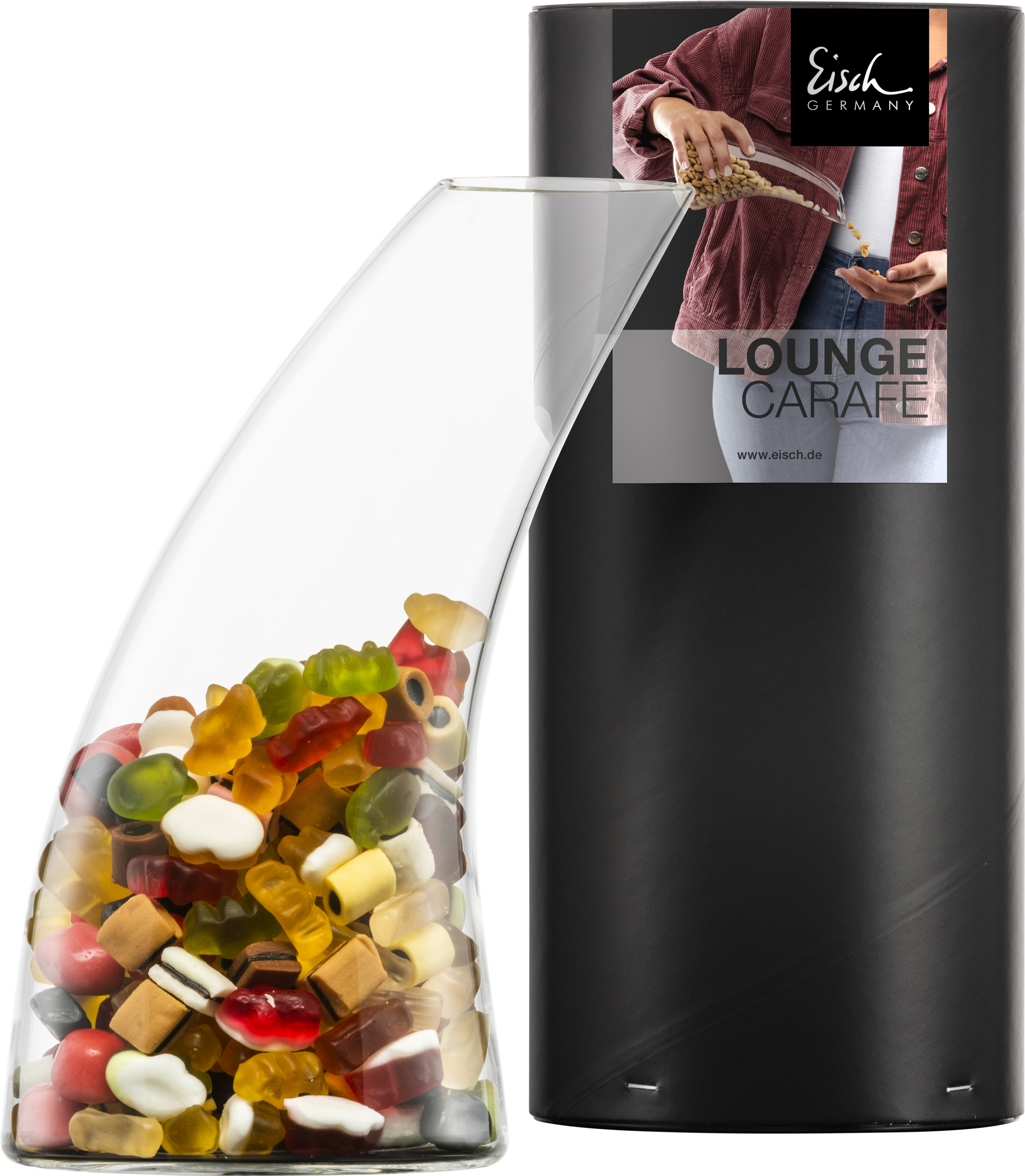 Ein Glasgefäß ist mit bunten Gummibärchen und Süßigkeiten gefüllt. Daneben steht eine schwarze Verpackung mit einem Etikett, auf dem eine Person etwas aus einem ähnlichen Gefäß schüttet.