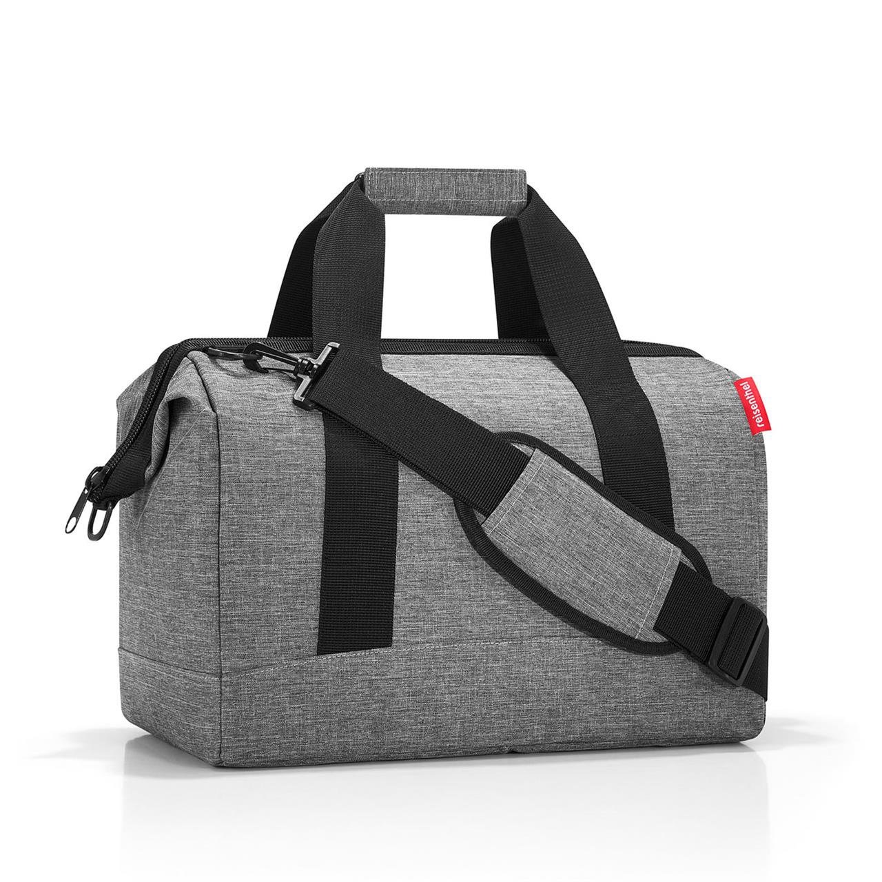 Die Abbildung zeigt die Reisetasche 'Allrounder M twist silver'. Sie ist grau mit schwarzen Tragegurten und einem Schulterriemen.
