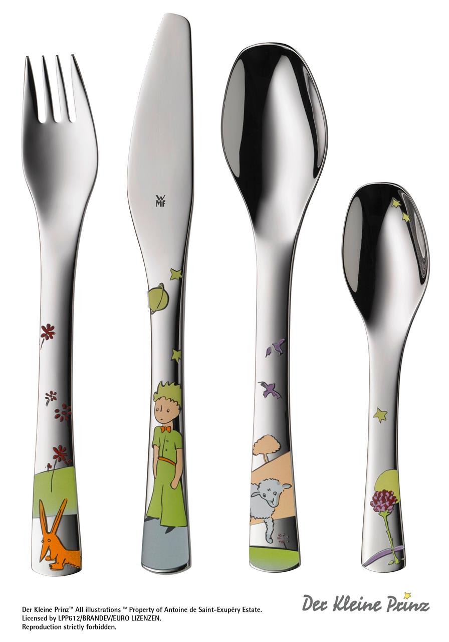Das Bild zeigt ein Kinderbesteck-Set mit vier Teilen, das mit Motiven aus "Der Kleine Prinz" verziert ist. Auf dem Besteck sind bunte Illustrationen des kleinen Prinzen und anderer Figuren aus dem Buch zu sehen.