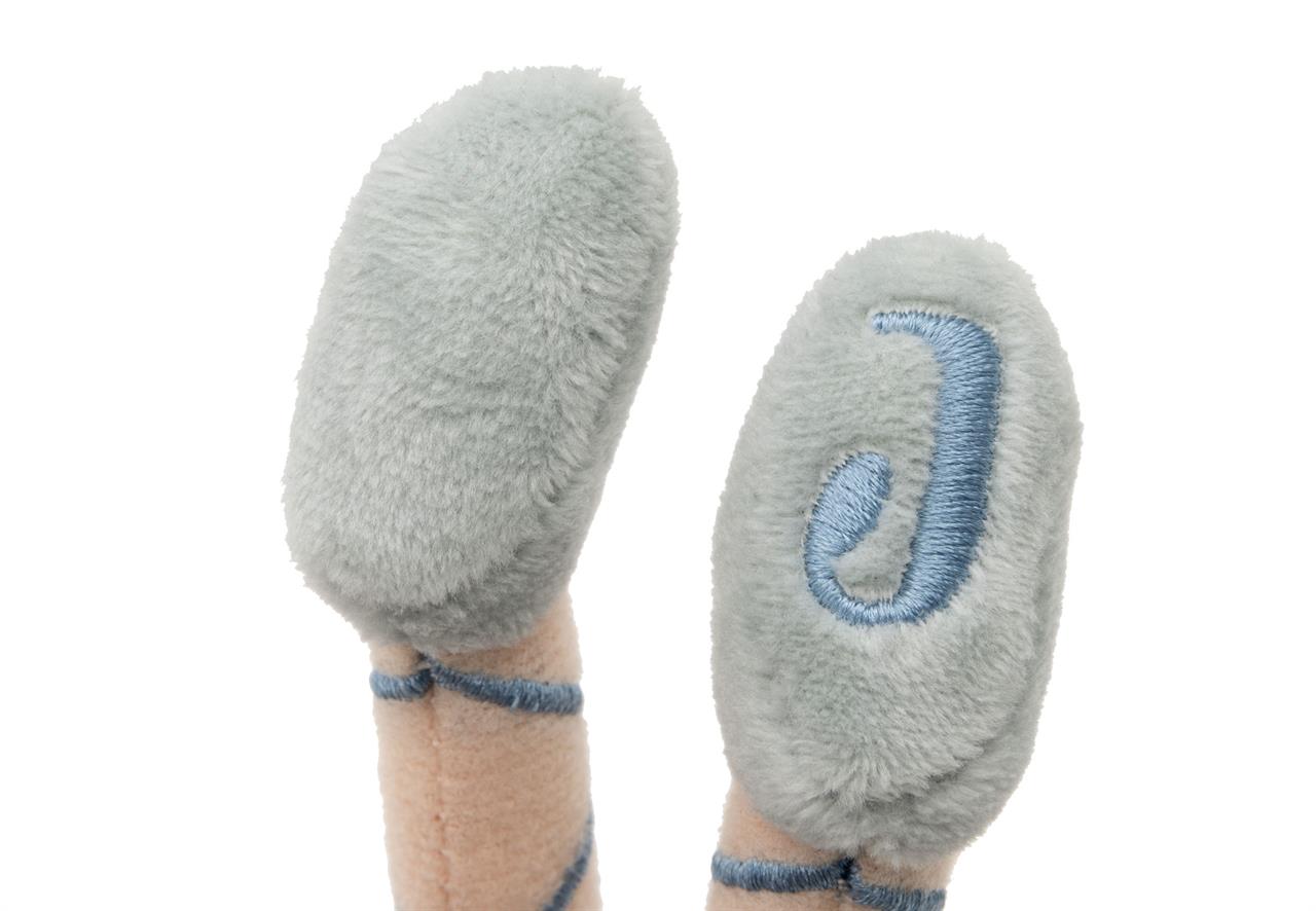 Das Bild zeigt die Füße eines Kuscheltiers mit hellgrauen, flauschigen Schuhen. Auf einem Schuh ist ein blauer Buchstabe "J" aufgestickt.