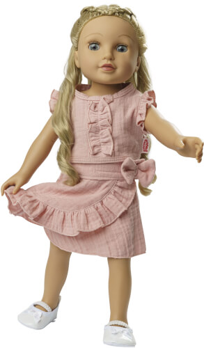 Das Bild zeigt eine Puppe mit langen blonden Haaren und blauen Augen. Sie trägt ein rosa Kleid mit Rüschen und eine Schleife an der Taille sowie weiße Schuhe.