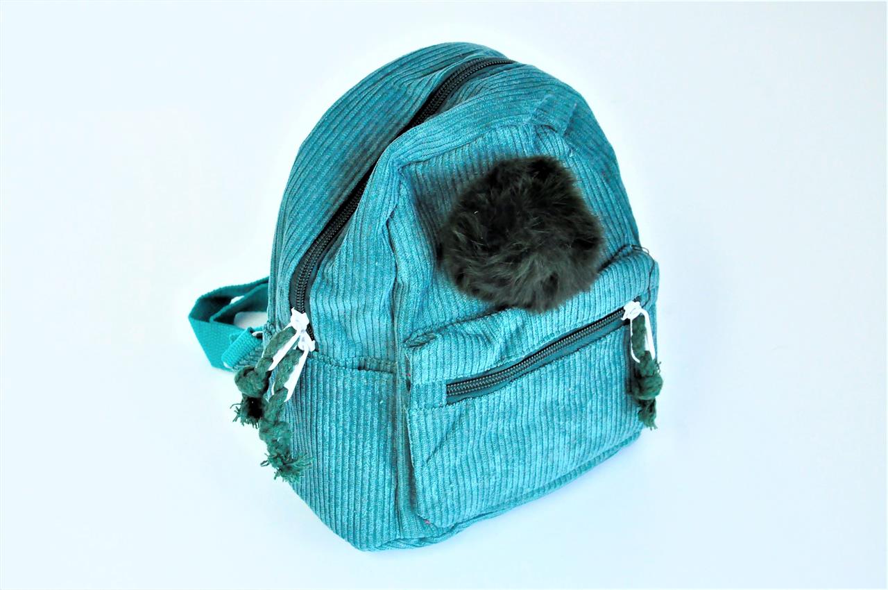 Der Rucksack ist aus grünem Cordstoff gefertigt und hat mehrere Reißverschlusstaschen. An der Vorderseite befindet sich ein schwarzer Bommel als Dekoration.