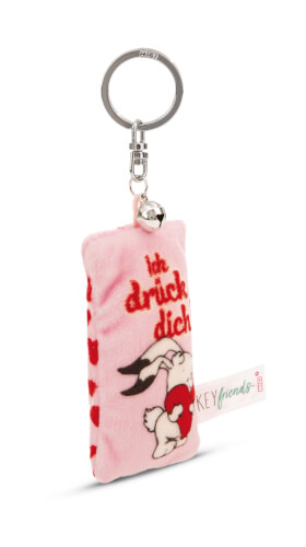 Auf dem Bild ist ein rosa, rechteckiger Plüsch-Schlüsselanhänger mit einem kleinen Hasen und roten Herzen zu sehen. Auf dem Anhänger steht in roter Schrift "Ich drück dich".