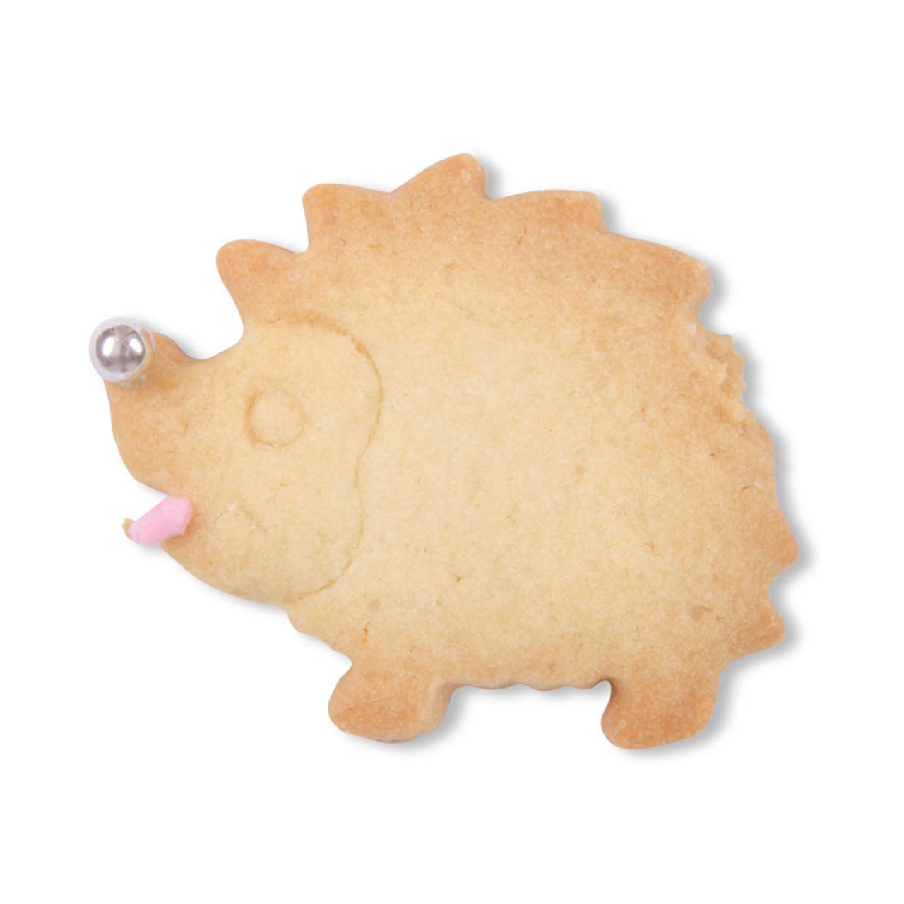 Auf dem Bild ist ein Keks in Form eines Igels zu sehen. Der Keks hat Verzierung für Nase und Zunge und sieht niedlich aus.