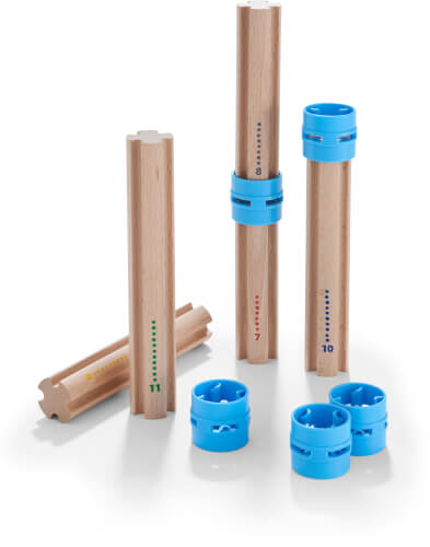 Auf dem Bild sind vier Holzstäbe mit aufgedruckten Zahlen und bunten Punkten zu sehen. Daneben liegen mehrere blaue Kunststoffringe auf dem Boden.