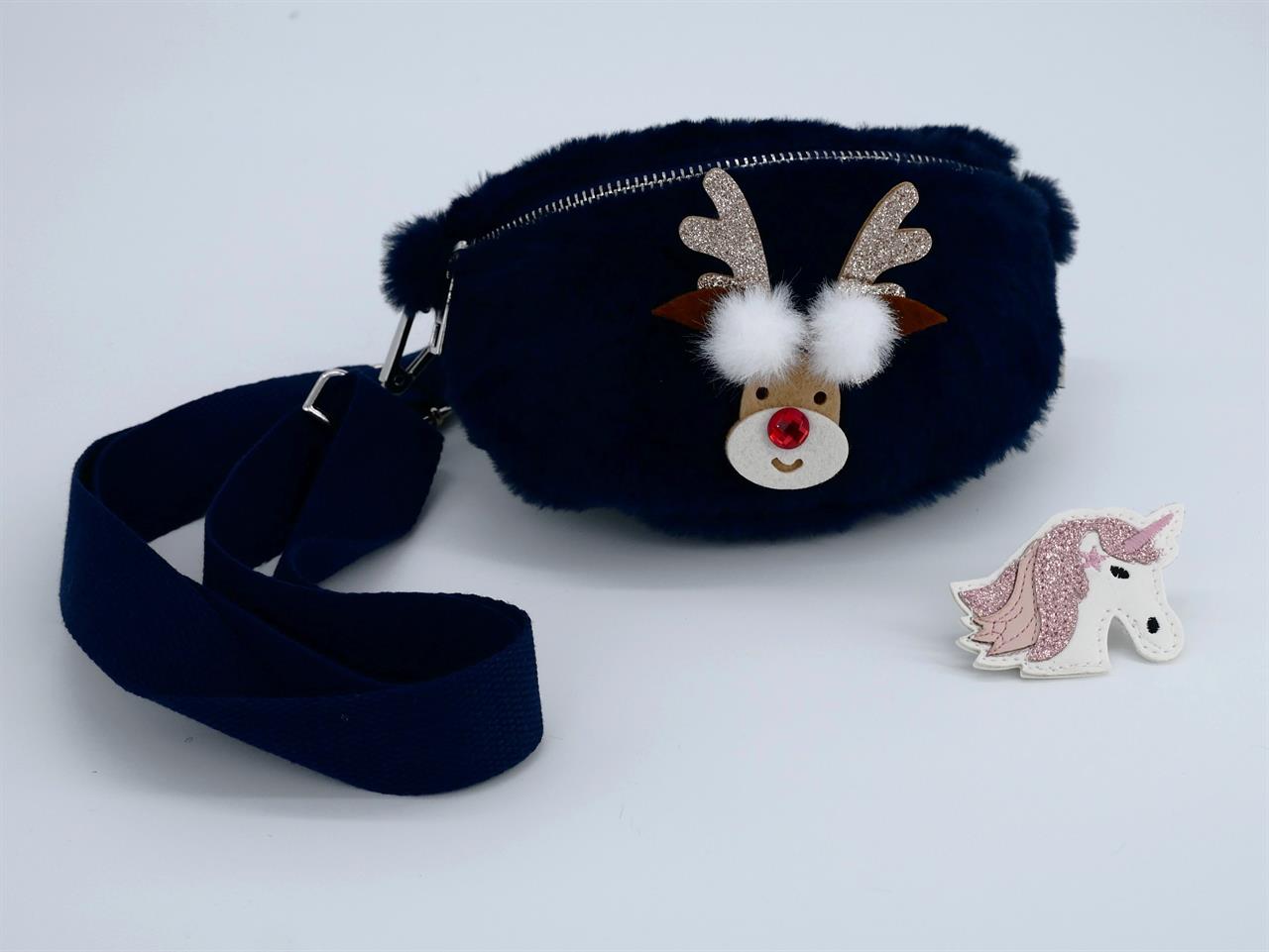 Auf dem Bild ist eine blaue Plüsch-Seitentasche mit einem Rentiermotiv zu sehen. Daneben liegt ein Aufnäher in Form eines Einhorns mit glitzernder Mähne.