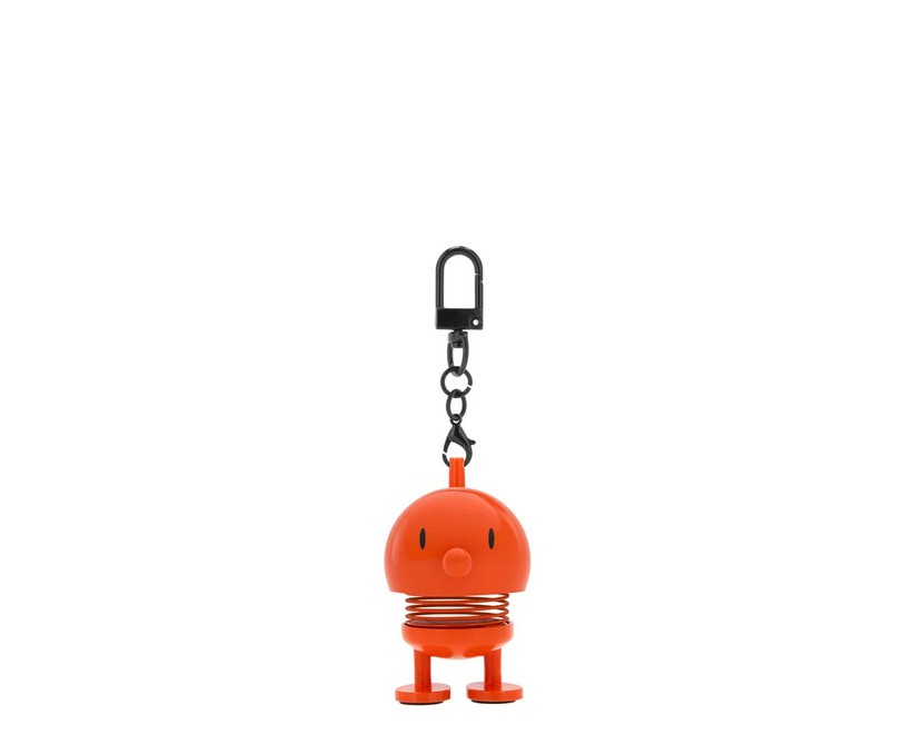 Ein Hoptimist Bag Charm in Orange wird gezeigt. Es handelt sich um einen kleinen, farbenfrohen Anhänger für Taschen.