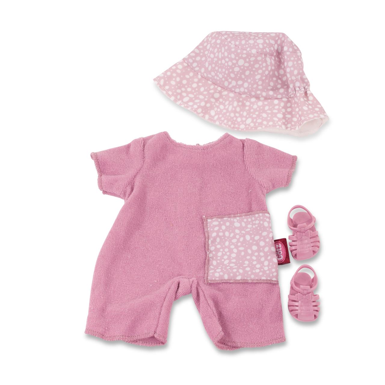 Das Bild zeigt ein sommerliches Babykleidungsset für Puppen in rosa Farbe. Das Set besteht aus einem kurzen Overall, einem Sonnenhut und einem Paar Sandalen.