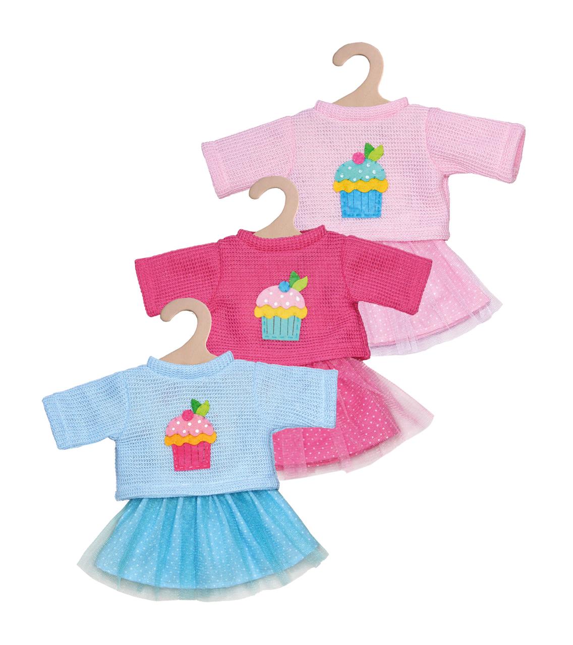 Das Bild zeigt drei verschiedene Puppenkleider-Sets, bestehend aus Pullover und Rock in den Farben Rosa, Pink und Blau. Jedes Set hat ein buntes Cupcake-Motiv auf dem Pullover.