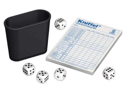 Das Bild zeigt einen Würfelbecher, fünf Würfel und einen Kniffel-Spielblock. Die Gegenstände werden für das Würfelspiel Kniffel verwendet.