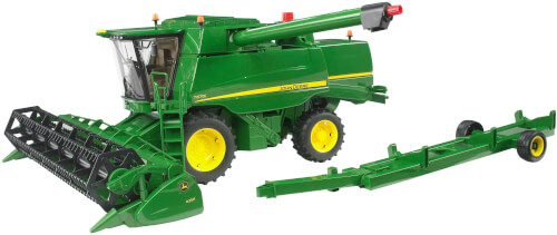 Das Bild zeigt eine grüne landwirtschaftliche Erntemaschine mit gelben Rädern. Daneben befindet sich ein abnehmbarer Vorsatz auf einem Anhänger.