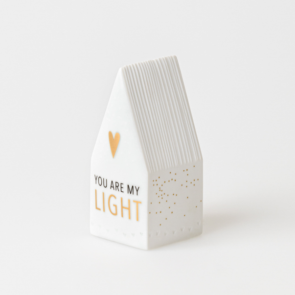 Das Bild zeigt ein kleines LED-Häuschen aus Keramik mit der Aufschrift „You Are My Light“. Es ist weiß mit goldenen Akzenten und hat ein Herz auf der Vorderseite.