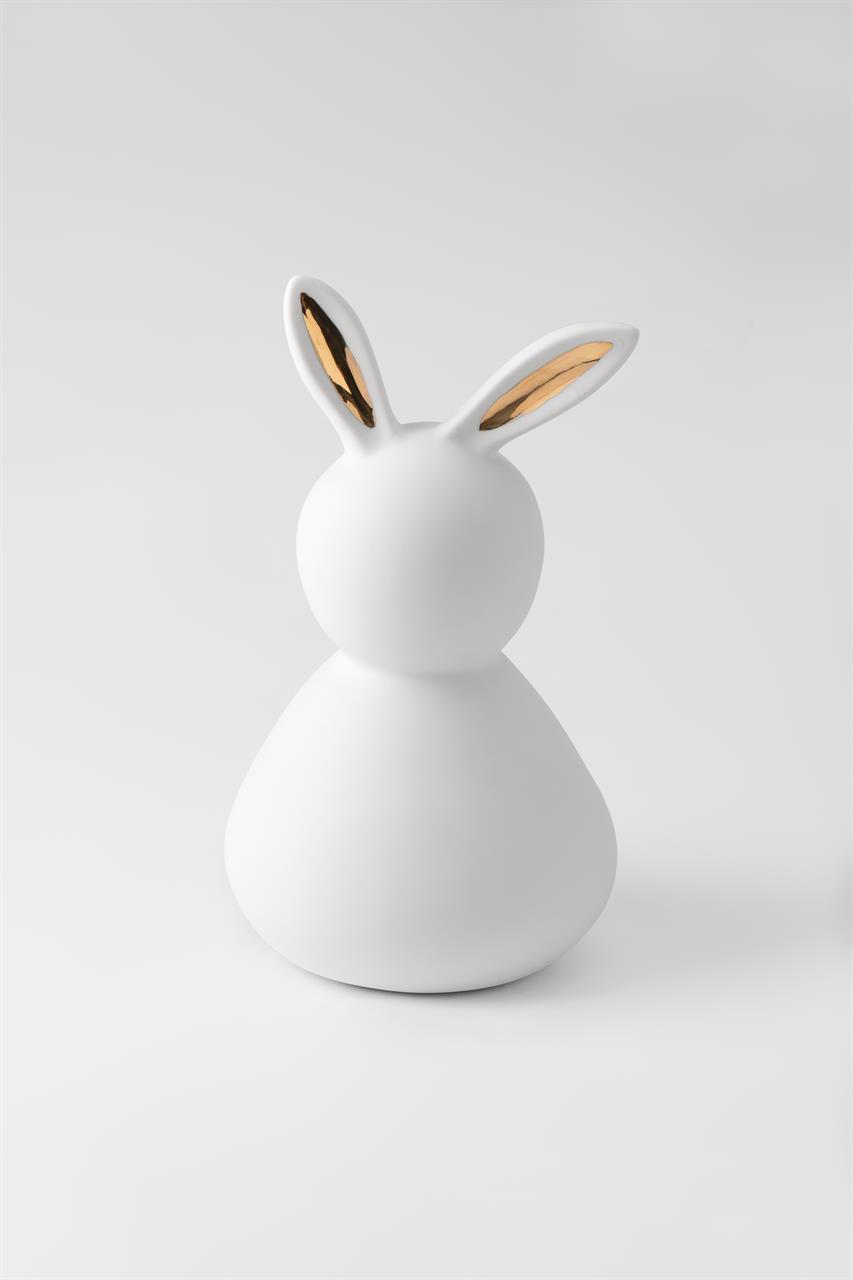 Die Abbildung zeigt einen großen Porzellanhasen mit goldenen Ohren. Die Figur ist schlicht weiß und hat eine moderne, minimalistische Form.