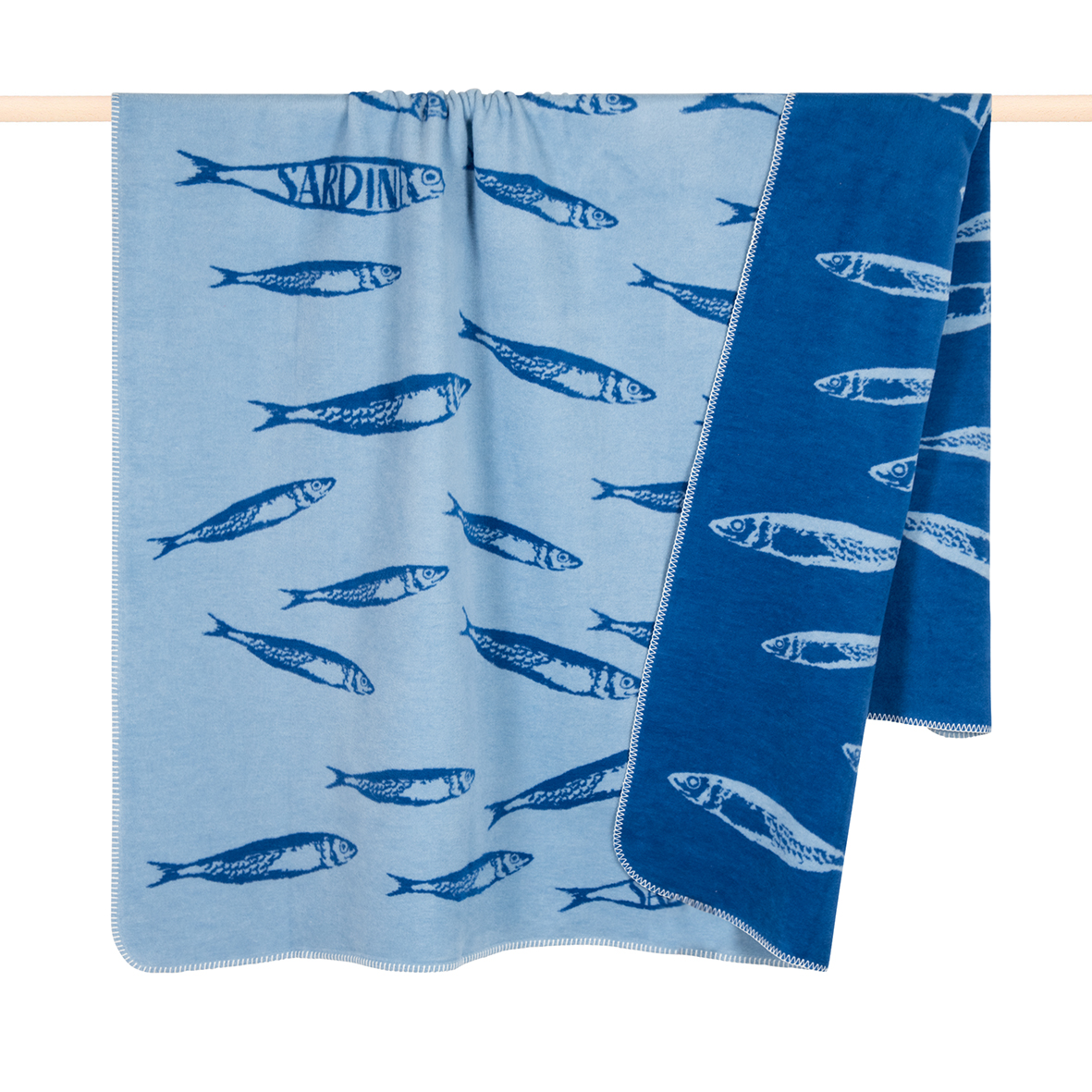 Die Decke "Fish" in Blau misst 150x200 cm und zeigt ein Muster aus Sardinen. Sie hat zwei verschiedene Blautöne mit Fischmotiven auf beiden Seiten.