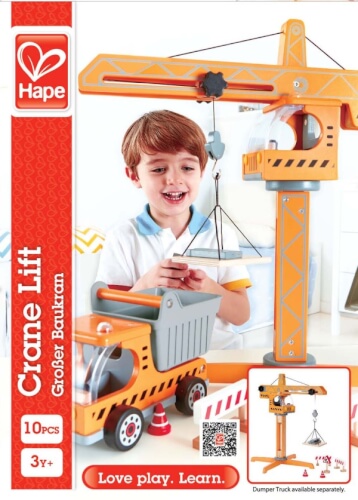 Ein Junge spielt mit einem Holz-Kran und einem Kipplaster. Das Spielzeug ist für Kinder ab 3 Jahren geeignet.