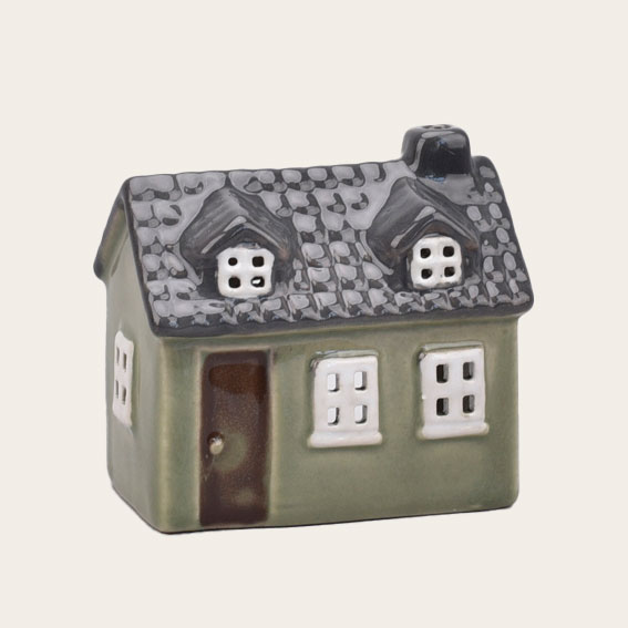 Ein kleines grünes Keramikhaus für Teelichter ist abgebildet. Das Produkt eignet sich als Dekoration und Lichtquelle.
